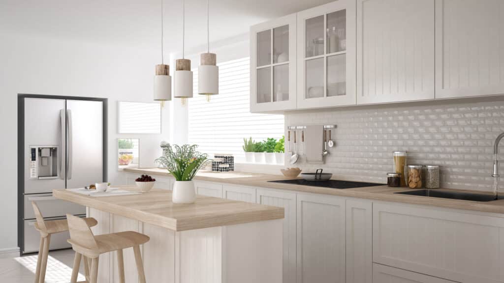 Cuisine moderne lumineuse avec îlot central en bois clair, armoires blanches, réfrigérateur inox et crédence en carreaux métro.