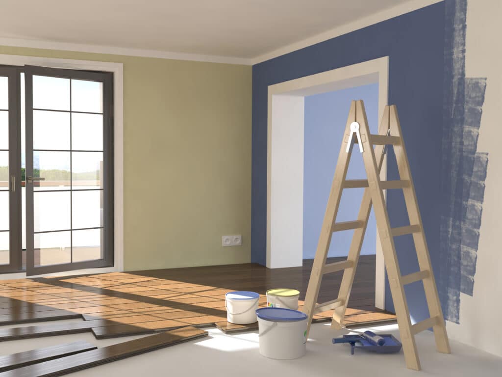 Pièce en rénovation : mur bleu en cours de peinture, parquet en bois posé et en attente, échelle, pots de peinture, lumière naturelle.