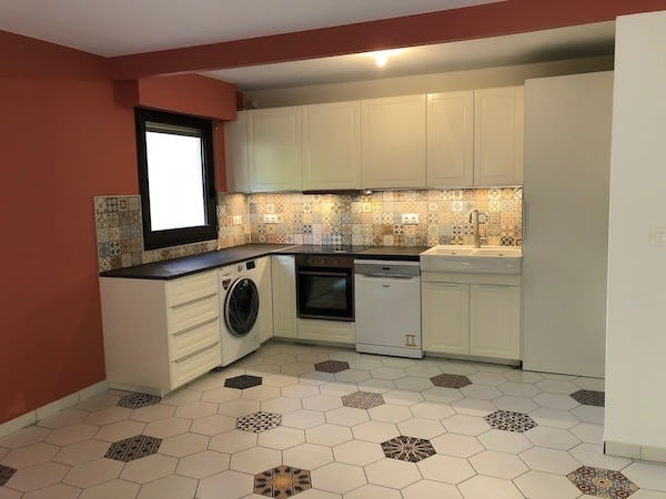 Cuisine moderne blanche avec crédence carreaux de ciment Cuisine moderne avec placards blancs, crédence en carreaux de ciment colorés et sol en carreaux hexagonaux blancs.