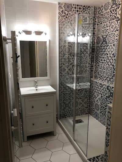 Salle de Bain Moderne avec Douche Italienne à Motifs Salle de bain moderne avec douche à l'italienne en carreaux de ciment bleus, vasque blanche et sol hexagonal blanc.